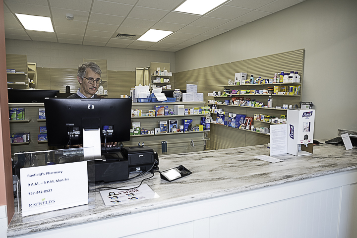 a man sitting at a desk in a pharmacy