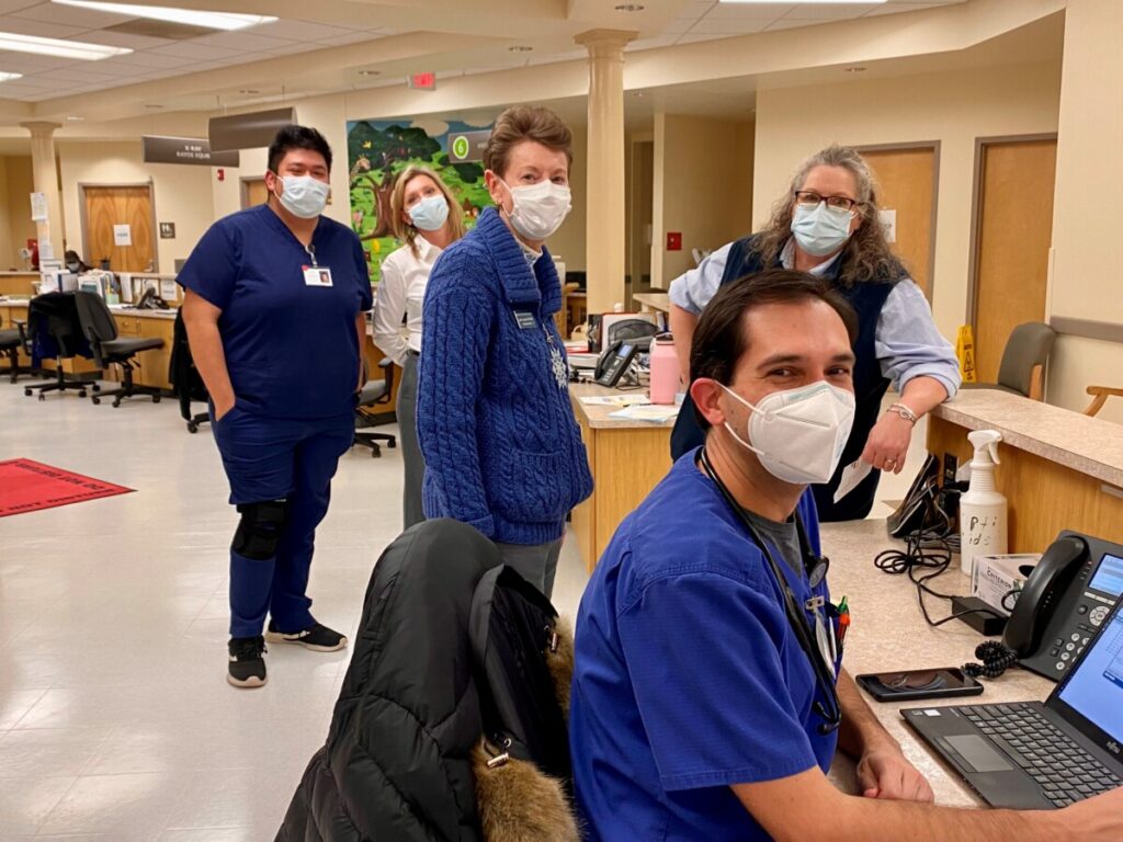 a group of people in scrubs and masks working on laptops