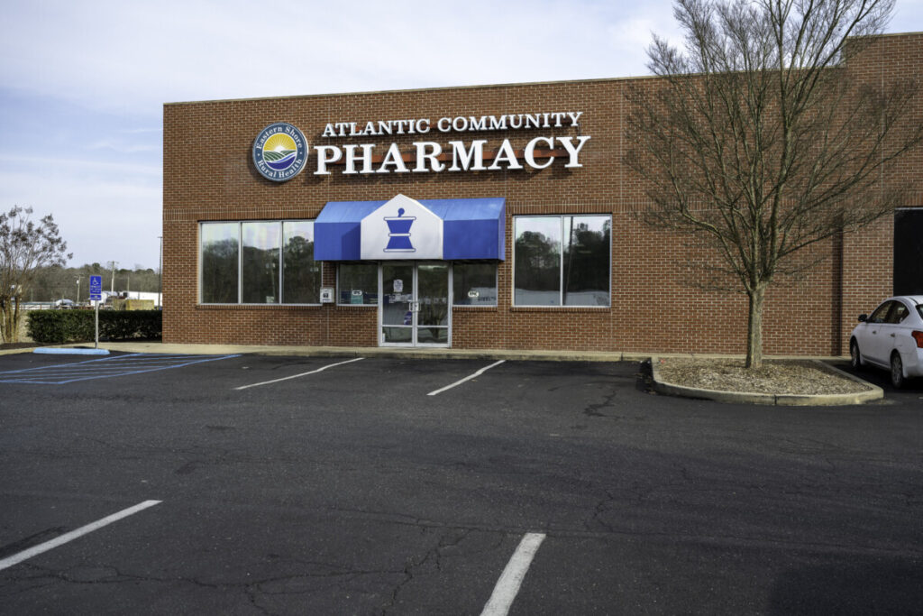 the front of a pharmacy building with a car parked outside