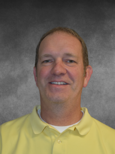 a man in a yellow shirt smiling at the camera