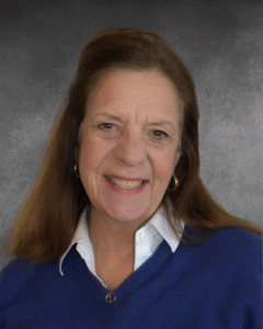 a woman in a blue sweater smiling at the camera
