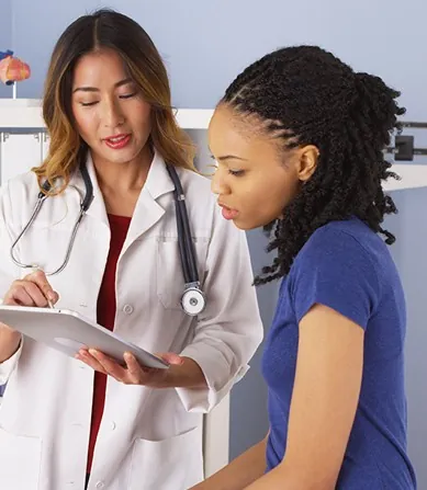 two women in white coats are looking at a clipboard