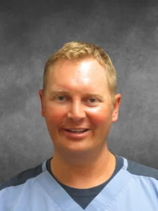 a man in a blue shirt is smiling at the camera
