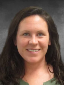 a woman in a green shirt smiling for the camera