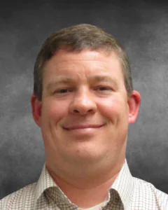 a man in a plaid shirt smiling for a picture