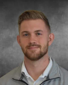 a man with a goatee and beard wearing a gray jacket