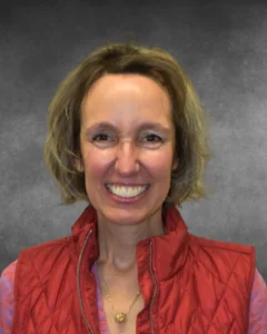a woman in a red vest smiling at the camera