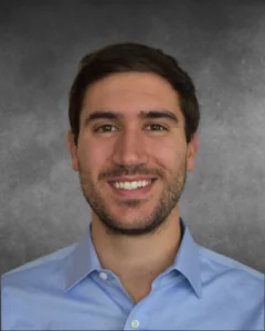 a man in a blue shirt smiling at the camera