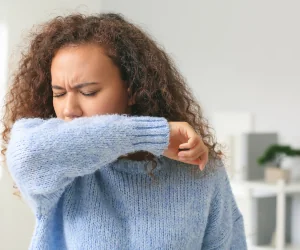 a woman covers her face with a sweater